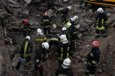 Ukrayna 'nın doğusundaki bir Rus füze saldırısından sonra kasklı ve koruyucu teçhizatlı bir grup kurtarma çalışanı molozların arasında arama yapıyor. Ukrayna 'da savaş, 2022