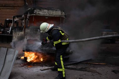 Bir itfaiyeci Ukrayna 'da devam eden savaşın ortasında bir Rus saldırısının ardından yanan bir araçla mücadele ediyor.