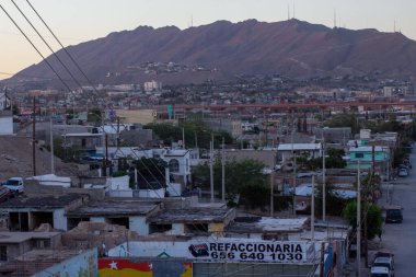 Alacakaranlıkta kentsel manzara, yoğun bir şekilde kalabalık yaşlanan binaları çarpıcı bir dağ zeminine vurguluyor, doğal ve inşa edilmiş çevrenin karışımını sergiliyor..