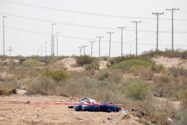 Battaniyeye sarılı iki erkek cesedi, Ciudad Juarez 'in ıssız bir bölgesinde, devam eden şehir şiddetinin ortasında terk edilmiş olarak yatıyor..