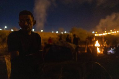 Ciudad Juarez yakınlarındaki bir göçmen kampında çıkan yangında, sınır ışıkları arka planı aydınlatıyor..