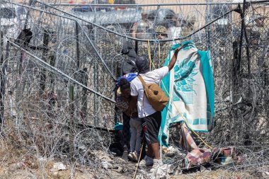 Siviller, Ciudad Juarez sınırında ağır çitlerle çevrili bir alanda ilerlerken, göçmenlik sorunlarını vurgulamak için battaniye kullanıyorlar..