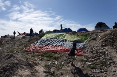 Ciudad Juarez 'deki geçici bir kampta geçici barınakların yanında yürüyen küçük bir çocuk, açık bir gökyüzü altında ABD-Meksika sınırında devam eden göç krizini yansıtıyor..