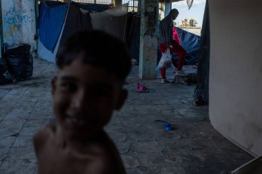 Genç çocuk, Ciudad Juarez sınırında kalabalık bir duvar yazısıyla dolu bir sığınağın arka planında gülümsüyor..