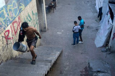 İnsan, göç zorluklarının ortasında grafiti yüklü Juarez sokağında merdivenlere suyla çıkıyor..