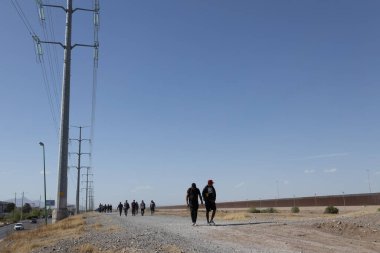 Göçmenler, Ciudad Juarez 'deki yüksek sınır duvarının yanında, açık bir gökyüzünün altında, ABD' ye geçiş için toplandılar..