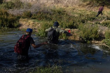 Amerika 'ya girmek için Ciudad Juarez yakınlarındaki bir nehirden geçen göçmenler..
