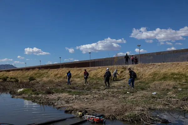 Göçmenler yüksek Ciudad Juarez sınır çitinin oradaki engebeli araziden geçiyorlar..