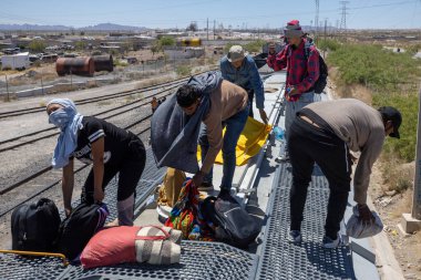 Göçmenler Ciudad Juarez yakınlarındaki tren rayları boyunca ağır çöl arazilerinde gerekli şeyleri taşıyorlar..
