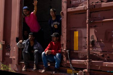 Ciudad Juarez yakınlarındaki bir yük treninden el sallayan adamlar, tehlikeli göçmen yolculuğunu simgeliyor..