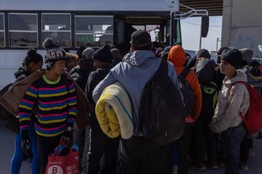 Göçmenler ve mülteciler Ciudad Juarez otobüs durağında kuyruğa girdiler..