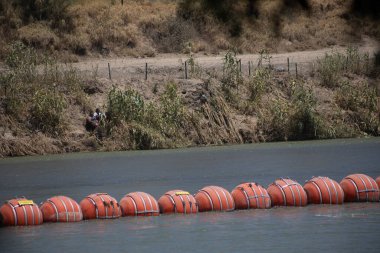 İnsanlar Rio Grande 'de yüzen bariyerlerin yanında dinleniyorlar, Ciudad Juarez' in orada, sınır geçişleri için sıcak bir nokta..