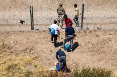 Göçmenler ve askerler Ciudad Juarez sınırında sohbet ediyorlar..