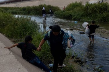 Göçmenler, Ciudad Juarez yakınlarındaki sığ Rio Grande 'yi geçerek ABD topraklarına girerken gerekli eşyaları taşıyorlar..