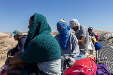 Göçmenler Ciudad Juarez yakınlarındaki bir yük treninin tepesine biniyor ve kuzeye, ABD sınırına doğru yaptıkları yolculuğun bir parçası olarak zorlu bir araziye çıkıyorlar..