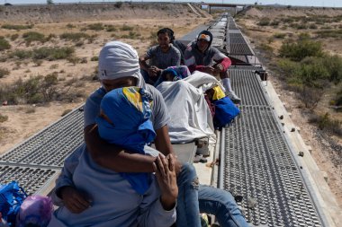 Göçmenler Ciudad Juarez yakınlarındaki bir yük treninin tepesine binip Amerika sınırına doğru olan kuzey yolculuklarının bir parçası olarak çöl arazisinden geçiyorlar..