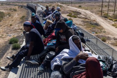 Göçmenler, Rio Grande 'ye varmadan önce Ciudad Juarez' in çöl kenar mahallelerinde durdurulan bir yük treninin üzerinde dinleniyorlar..