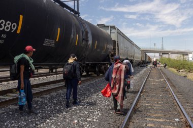 Göçmenler Ciudad Juarez 'de yük trenleriyle yürüyüp açık bir gökyüzünün altında kuzeye giden yolları arıyorlar..