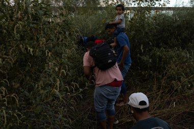 Aralarında bir çocuğun da bulunduğu göçmenler Ciudad Juarez yakınlarındaki yoğun çalılıklarda geziniyorlar..