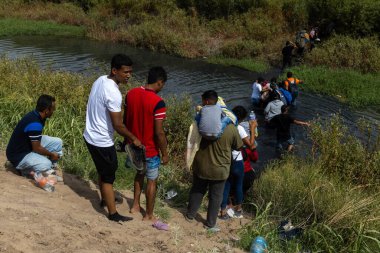 Siviller Ciudad Juarez yakınlarındaki bir nehirde yol alırken, göçmenlik sorunlarının ortasında eşyalar taşıyorlar..