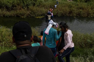 Çocuklar da dahil olmak üzere siviller, göç sorunları arasında Ciudad Juarez sınırındaki bir nehirde yol alıyorlar..