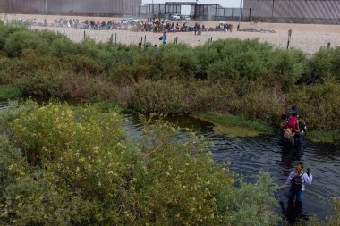 Siviller Ciudad Juarez sınırı yakınlarındaki bir nehirde gezinerek, sürekli göç sorunlarını yansıtıyorlar..
