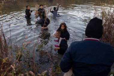Çocuklar da dahil olmak üzere siviller, Ciudad Juarez yakınlarında bir göç noktası olan bir nehirde yol alıyorlar..