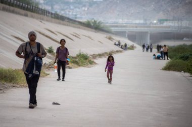 Aralarında ailelerin de bulunduğu siviller, pek çok göçmenin ayak bastığı Ciudad Juarez 'deki beton kanalda geziniyorlar..