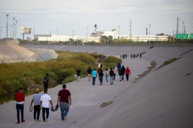 Göçmenler, ABD sınırına yakın Ciudad Juarez yakınlarında beton bir nehir yatağında yol alıyorlar..