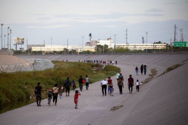 Göçmenler Ciudad Juarez sınır bölgesine giden büyük bir kanalda yol alıyorlar..