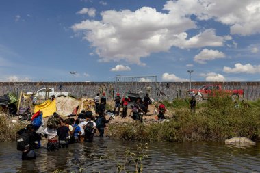 Göçmenler Ciudad Juarez sınırındaki sularda geziniyorlar, geçici barınaklarla çevrili..