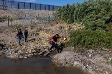 Göçmenler Meksika 'ya geçtikten sonra ABD sınır duvarına doğru Ciudad Juarez' deki Rio Grande 'nin yanından geçici bir patika boyunca yürüyorlar..