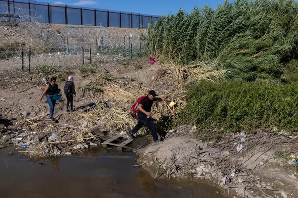 Göçmenler Meksika 'ya geçtikten sonra ABD sınır duvarına doğru Ciudad Juarez' deki Rio Grande 'nin yanından geçici bir patika boyunca yürüyorlar..