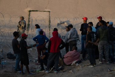 Göçmenler, Rio Grande 'yi geçtikten sonra askeri personelin gözetiminde gün batımında Ciudad Juarez' deki sınır çitlerinde toplandılar..