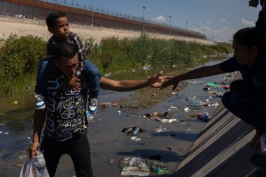 İnsan ve çocuk, Ciudad Juarez sınırındaki kirli nehirde dolaşarak göç sorunlarını vurguluyor..
