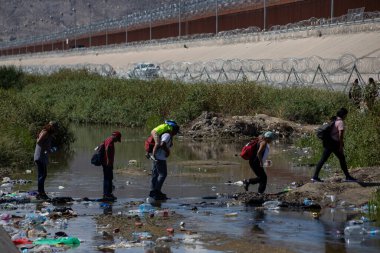 Göçmenler, Ciudad Juarez 'deki güçlendirilmiş sınır çiti yakınlarındaki enkaz dolu Rio Grande' de geziniyorlar..