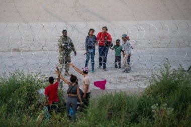 Göçmenler, Ciudad Juarez 'deki sınır çiti yakınlarında bir askerle temas kurarak, ABD' ye düzensiz göç konusunda devam eden gerginliği vurguluyor..