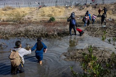 Aileler, zorluklardan kaçmak için Ciudad Juarez sınırındaki çamurlu bir nehirde yol alıyorlar..
