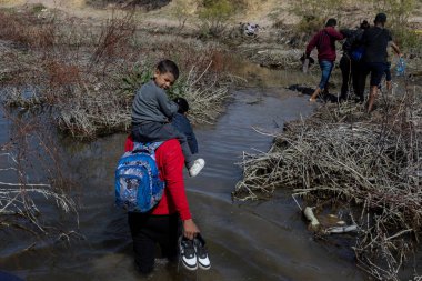Çocuklar da dahil olmak üzere, göçmenler Ciudad Juarez 'de bir nehirde yol alıyorlar..