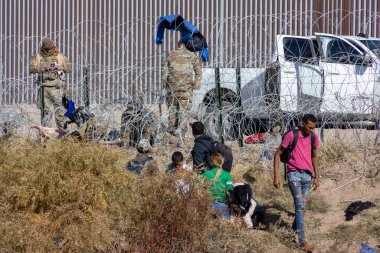 Ciudad Juarez 'deki tahkim edilmiş sınır duvarının yakınındaki göçmenler Teksas Ulusal Muhafız askerlerinin gözetiminde..