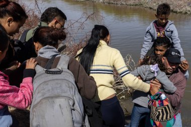 Göçmenler, çocuklar da dahil, Amerika 'ya geçmek için Ciudad Juarez yakınlarındaki Rio Grande' de bekleyin..