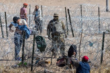 Göçmenler, Ciudad Juarez 'deki sınır duvarı yakınındaki Teksas Ulusal Muhafız birliklerinin gözetimi altında akordiyon tellerinde geziniyorlar..