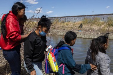 Sırt çantalı göçmenler, Ciudad Juarez yakınlarındaki Rio Grande boyunca korunan sınır çitlerinin yanında toplandılar..