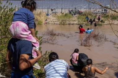 Aralarında bir çocuğun da bulunduğu göçmenler, düzensiz bir sınır geçişi sırasında Ciudad Juarez yakınlarındaki çamurlu Rio Grande 'yi geçtiler..