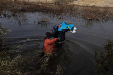 İki göçmen Rio Grande 'nin karşısında Ciudad Juarez' de sığınma hakkı aramak için eşyalar taşıyorlar..