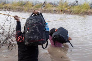 Sırt çantalı göçmenler, Rio Grande 'yi geçerek Ciudad Juarez' in yakınından geçiyorlar..
