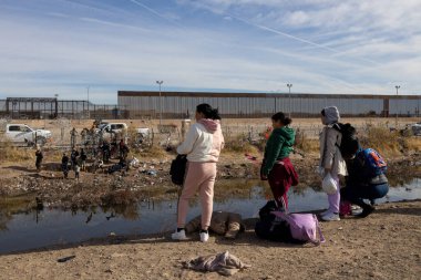 Bavullu göçmenler, sınırı geçmek için Ciudad Juarez yakınlarındaki Rio Grande 'de bekliyorlar..