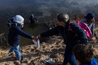 Bir kadın, düzensiz bir sınır geçişi sırasında Rio Grande 'den geçen bir adama yardım ediyor..