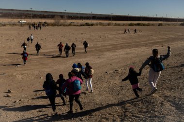 Çocuklar da dahil olmak üzere göçmenler, Ciudad Juarez 'deki sınır duvarına, düzensiz geçişler sırasında kullanılan ortak bir rotayı takip ederek yaklaşıyorlar..