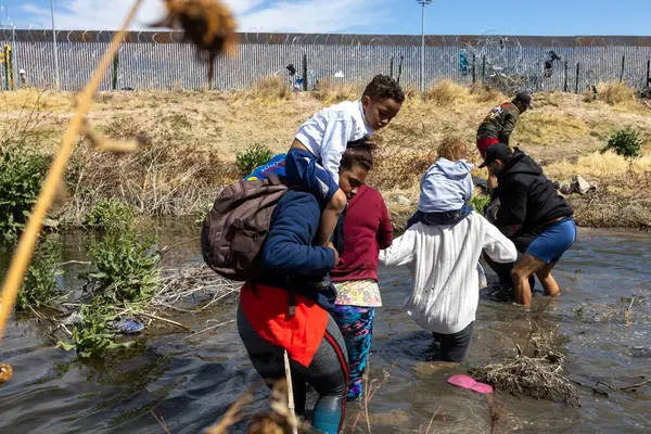 Çocuklar da dahil olmak üzere siviller, Ciudad Juarez sınırındaki bir nehirde yol alıyorlar ve zorluklardan kaçıyorlar..